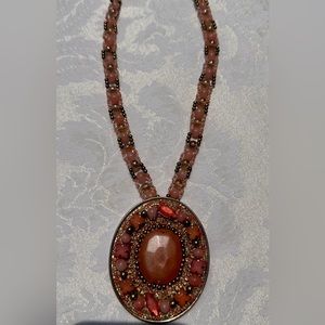 Orange beaded necklace that lands high on chest.